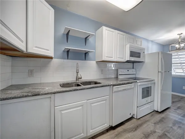 a kitchen with granite countertop white cabinets white stainless steel appliances and sink