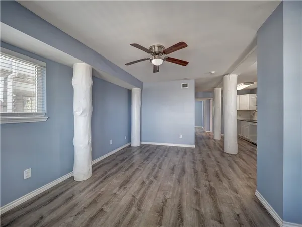 a view of empty room with wooden floor and fan