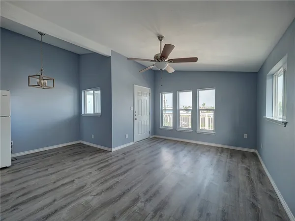 a view of an empty room with a window and wooden floor