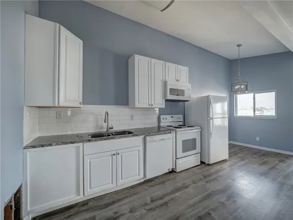 a kitchen with granite countertop white cabinets and white appliances