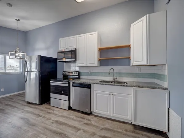 a kitchen with granite countertop a refrigerator sink and microwave