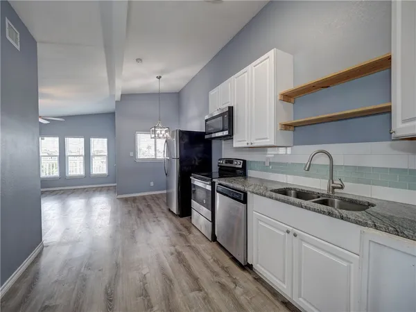 a kitchen with kitchen island granite countertop a sink cabinets and wooden floor