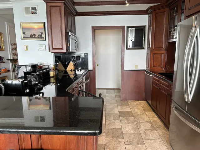 a kitchen with kitchen island granite countertop a refrigerator and a stove