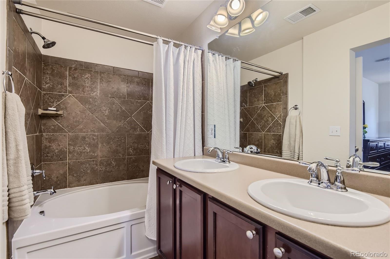 10495 Rutledge Street Parker, CO 80134 - Photo 16 of 32 a bathroom with a sink double vanity mirror and a bathtub