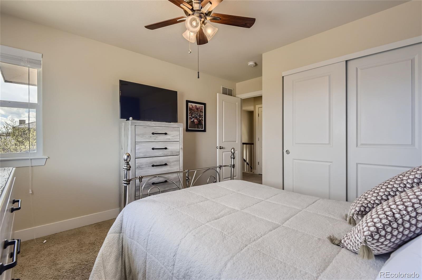 10495 Rutledge Street Parker, CO 80134 - Photo 19 of 32 a bedroom with a bed and a flat screen tv