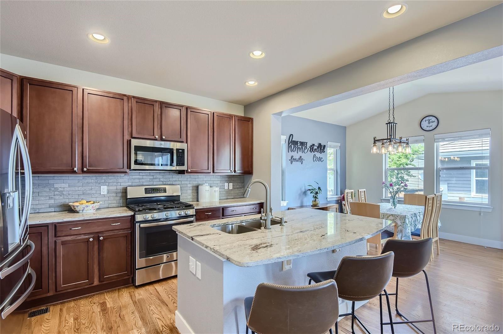 10495 Rutledge Street Parker, CO 80134 - Photo 7 of 32 a kitchen with stainless steel appliances kitchen island granite countertop a sink and cabinets