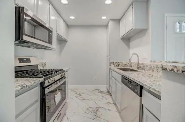 a kitchen with stainless steel appliances granite countertop a lot of cabinets a stove and a sink