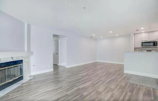 a view of empty room with wooden floor and fireplace