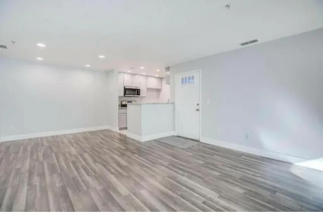 a view of a kitchen with a microwave and wooden floor