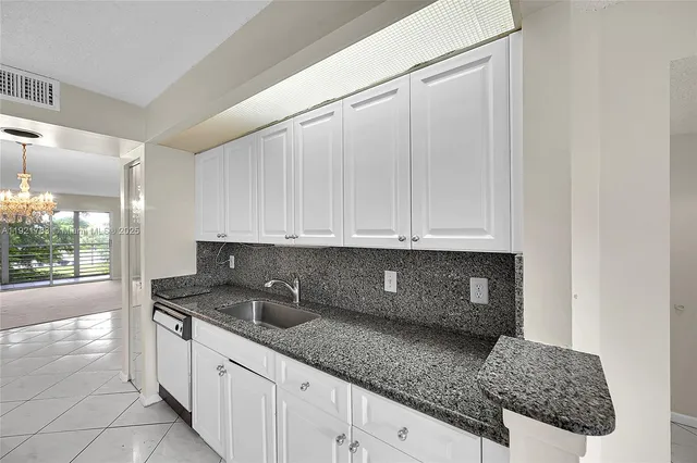 a kitchen with granite countertop a sink stove and cabinets