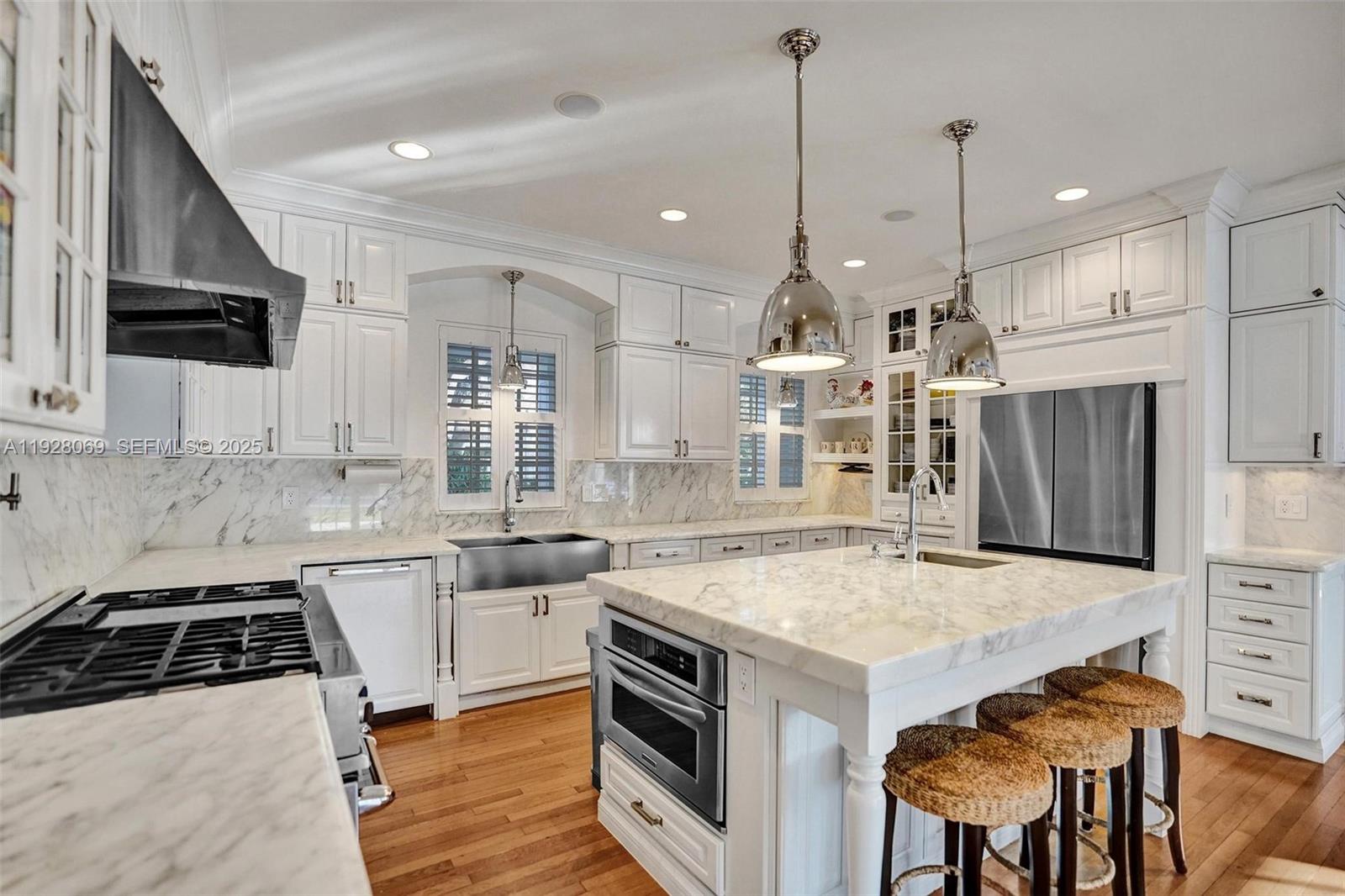1281 Banyan Road Boca Raton, FL 33432 - Photo 33 of 69 a kitchen with a stove a sink a kitchen island with chairs and wooden cabinets