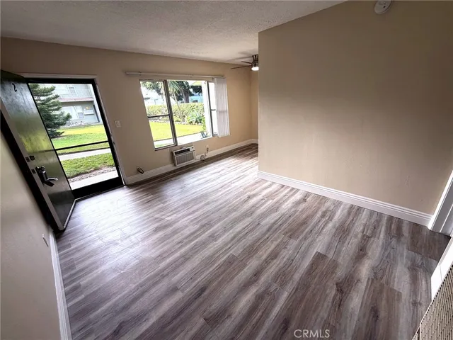 a view of an empty room with a window and wooden floor