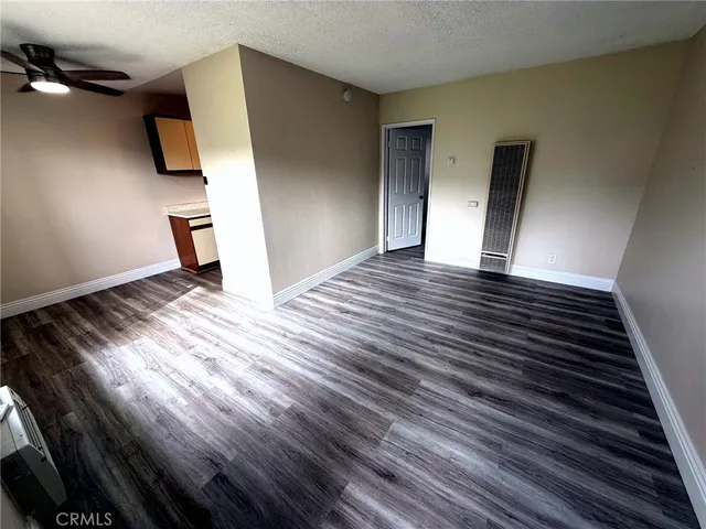 a view of an empty room with wooden floor and window