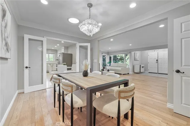 a dining room with wooden floor a chandelier a wooden table and chairs