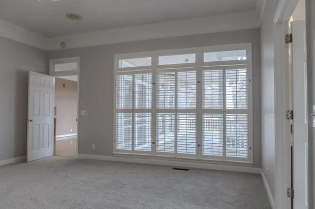 an empty room with a chandelier fan and windows