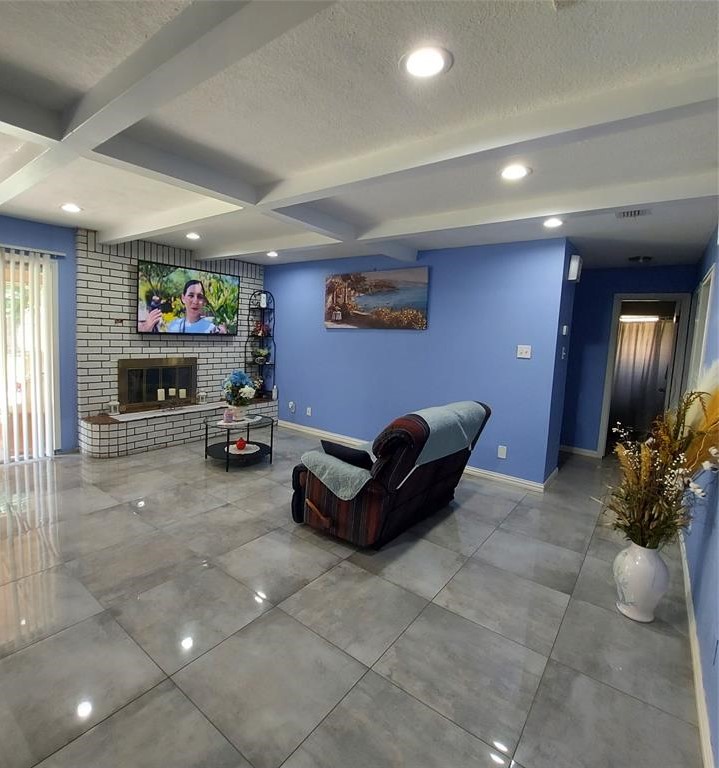 A view of the Living area featuring a Floor-to-ceiling brick   Fireplace, Recessed Lighting, and a Coffered Ceiling.

