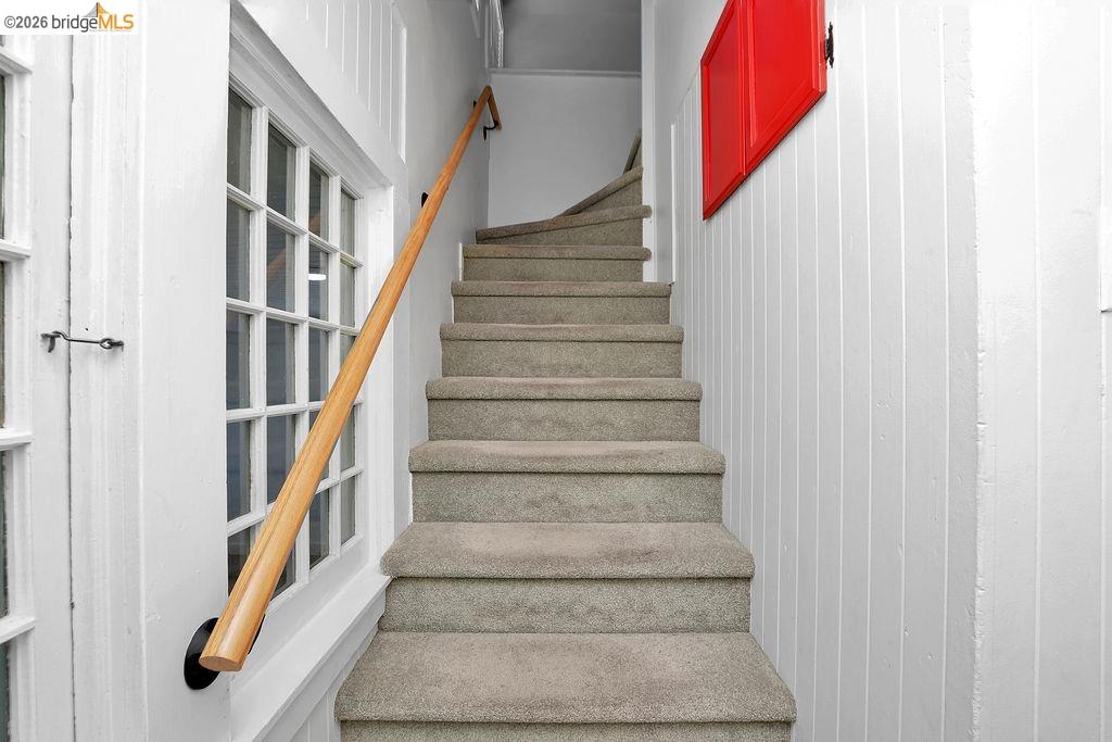 325 South 2nd Street Rio Vista, CA 94571 - Photo 18 of 33 Carpeted staircase featuring a light wood handrail with black mounts, beadboard wall paneling, and a multipane window