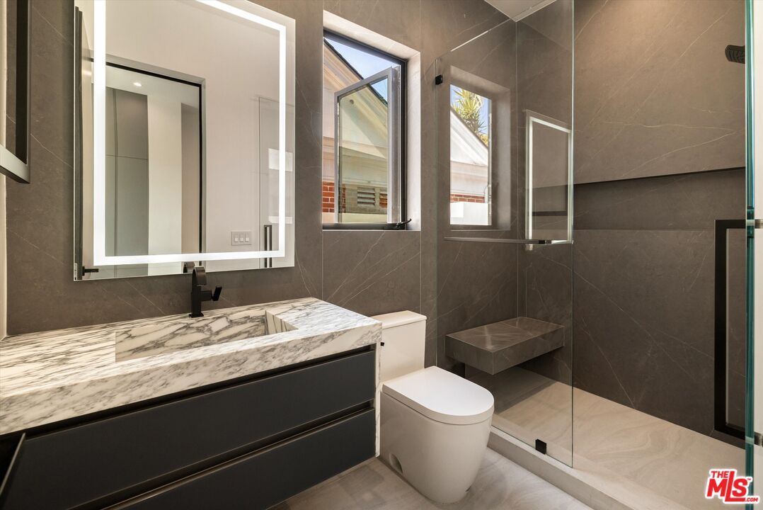 621 North Rodeo Drive Beverly Hills, CA 90210 - Photo 15 of 28 a bathroom with a granite countertop toilet sink and mirror