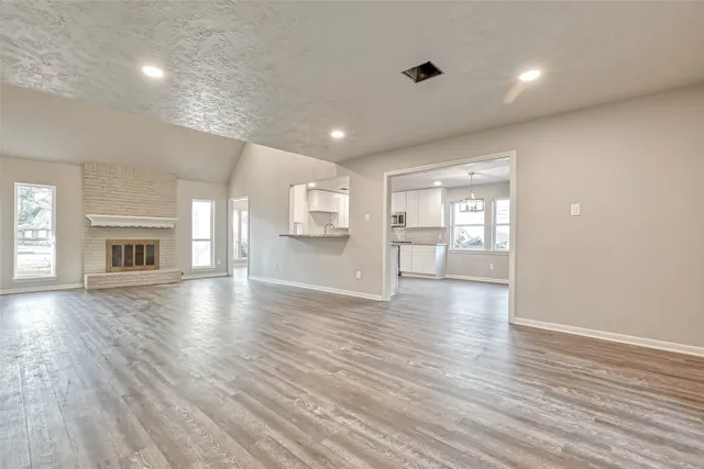 a view of an empty room with window and wooden floor
