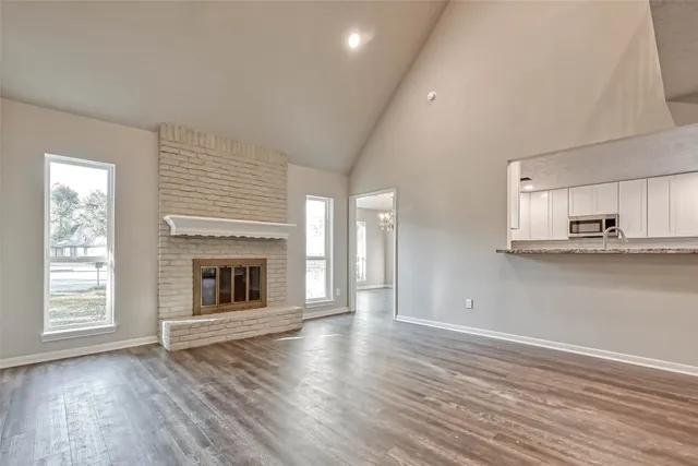 an empty room with wooden floor fireplace and windows