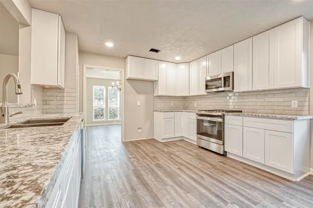 a kitchen with granite countertop a sink stove and refrigerator