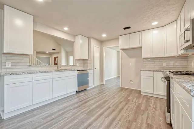 a large kitchen with cabinets wooden floor and stainless steel appliances