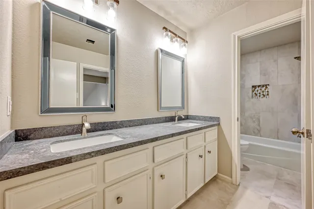 a bathroom with a granite countertop double vanity sink and mirror