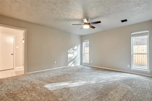 an empty room with windows and ceiling fan
