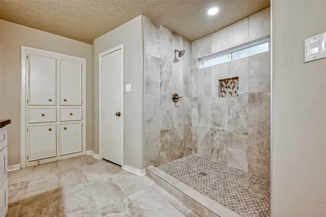 a bathroom with a granite countertop sink a mirror and shower