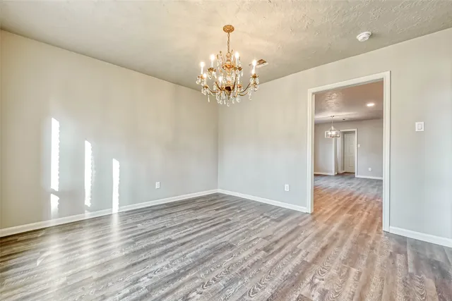 a view of a chandelier in big room with wooden floor