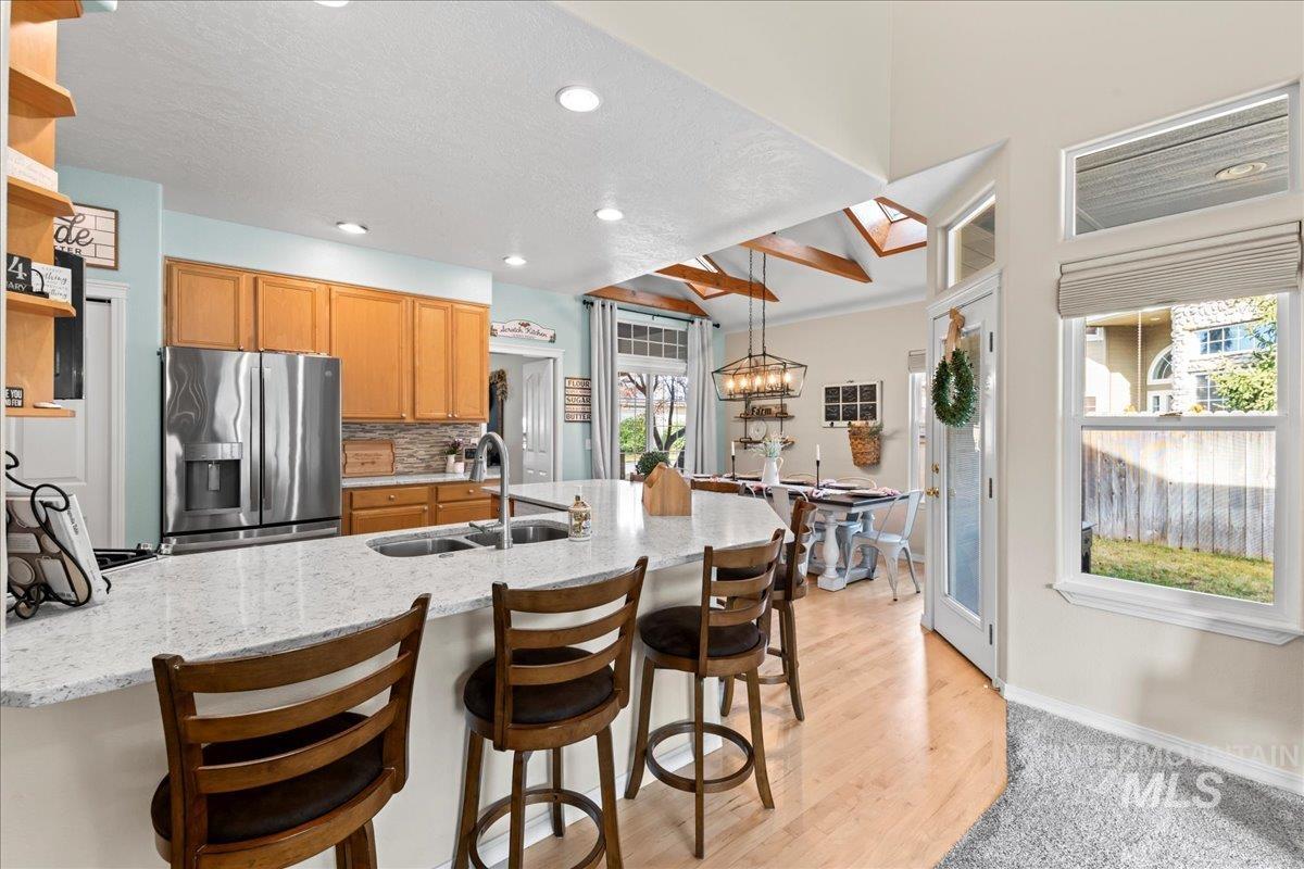 6326 North Talcrest Place Boise, ID 83713 - Photo 11 of 34 Kitchen featuring stainless steel fridge with ice dispenser, a kitchen bar, backsplash, a peninsula, and beam ceiling