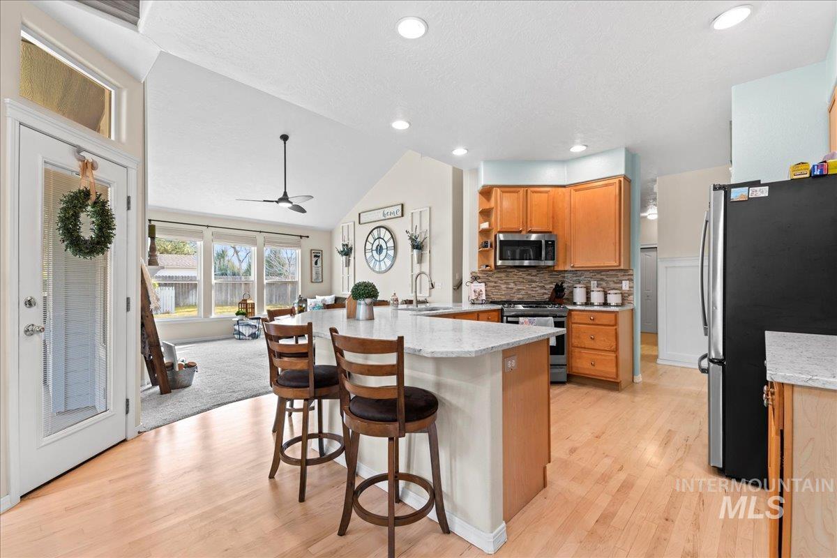 6326 North Talcrest Place Boise, ID 83713 - Photo 13 of 34 Kitchen with stainless steel appliances, a breakfast bar area, vaulted ceiling, a peninsula, and light wood-style floors