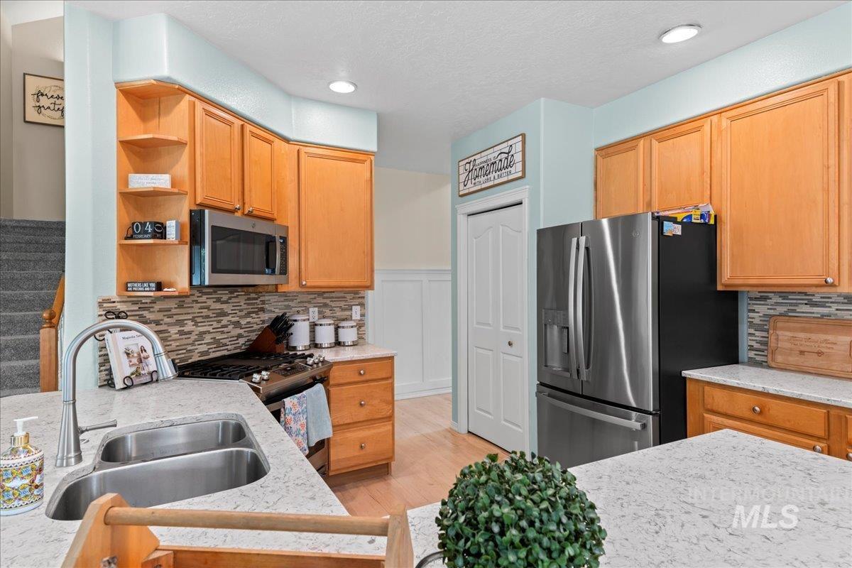 6326 North Talcrest Place Boise, ID 83713 - Photo 16 of 34 Kitchen featuring decorative backsplash, open shelves, stainless steel appliances, light wood-type flooring, and light stone countertops