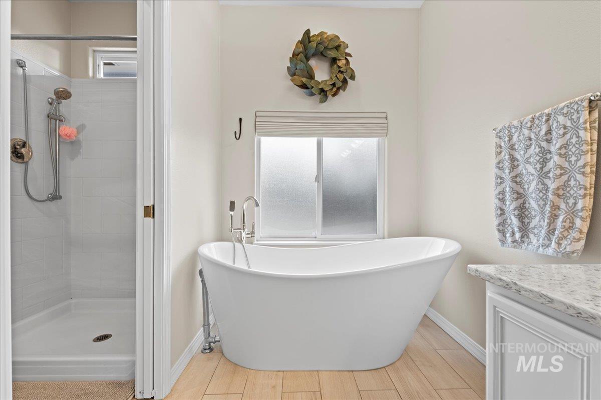 6326 North Talcrest Place Boise, ID 83713 - Photo 22 of 34 Full bath with healthy amount of natural light, a soaking tub, a stall shower, and wood finish floors