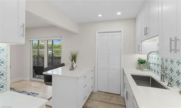 a kitchen with white cabinets and sink