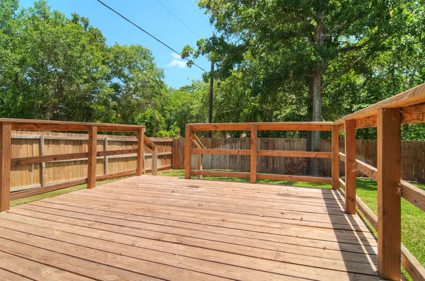 a view of house with deck outdoor seating and trees in the background