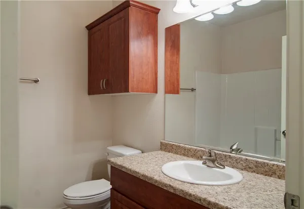 a bathroom with a granite countertop sink a toilet and mirror
