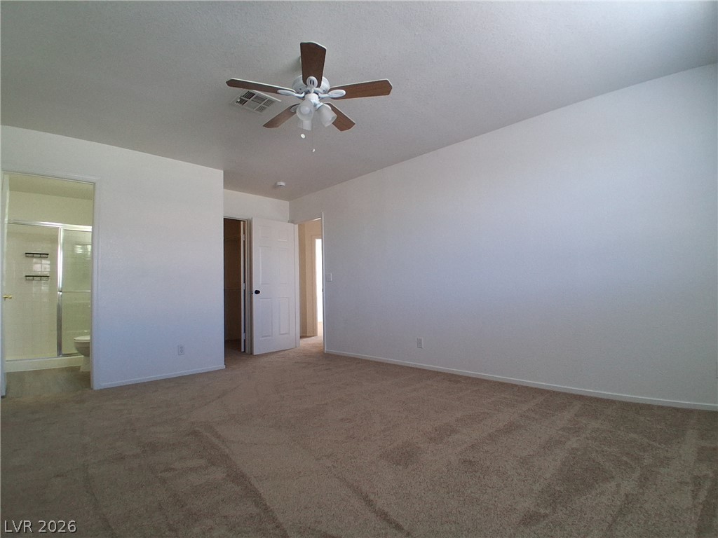 8023 Simone Avenue Las Vegas, NV 89147 - Photo 10 of 12 A spacious primary bedroom features soft carpeting and direct access to an ensuite bathroom.