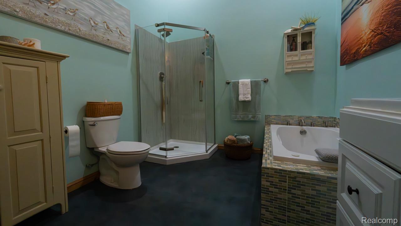 2418 South 41st Road South Cadillac, MI 49601 - Photo 42 of 57 Bathroom featuring a glass-enclosed shower, built-in soaking tub with mosaic tile surround, white toilet, and dark flooring