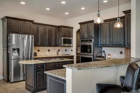 a kitchen with kitchen island granite countertop stainless steel appliances and wooden cabinets