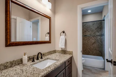 a bathroom with a granite countertop sink and a mirror