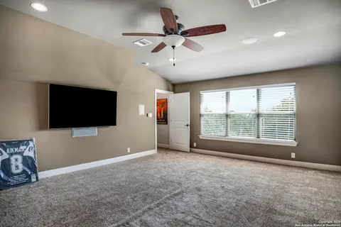 a view of an empty room with a flat screen tv and a ceiling fan