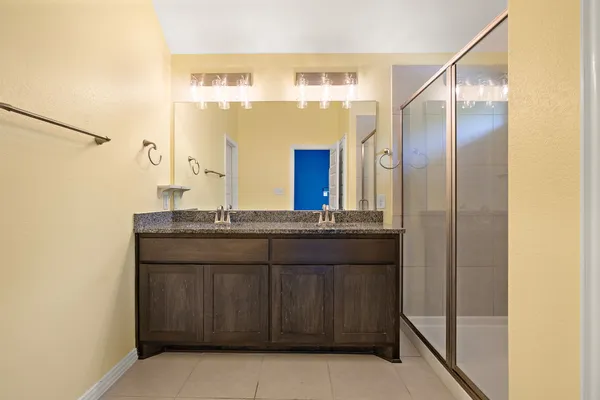 a bathroom with a granite countertop sink a mirror and a shower