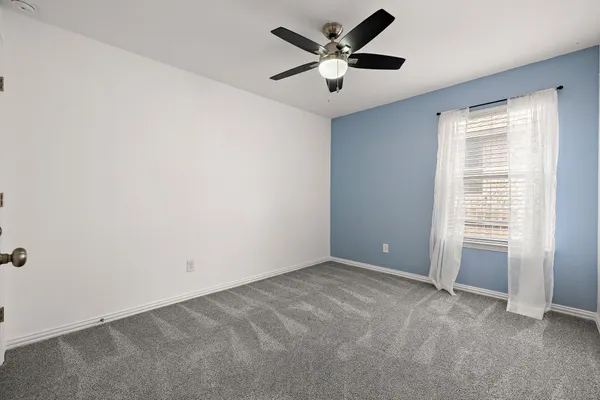 an empty room with windows and fan