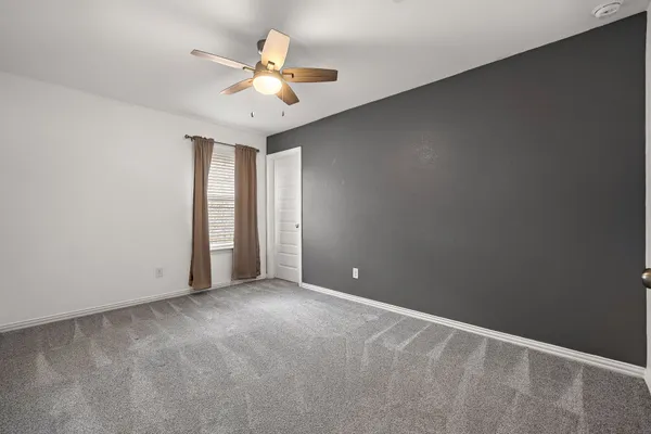 an empty room with a chandelier fan and windows