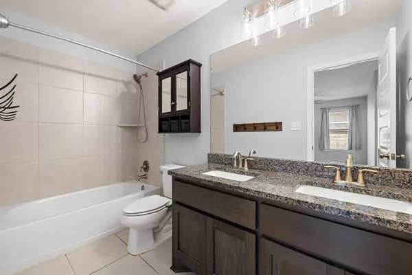 a bathroom with a granite countertop sink toilet mirror and bathtub