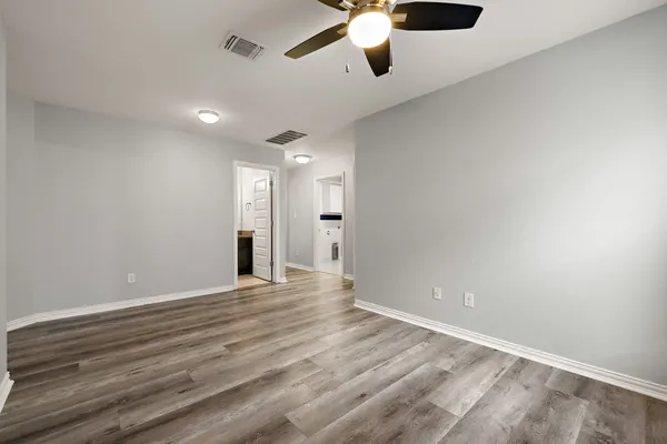 an empty room with chandelier fan and windows