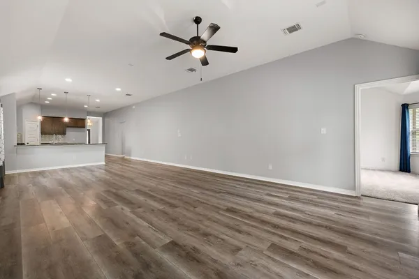 a view of a livingroom with a ceiling fan wooden floor and a ceiling fan