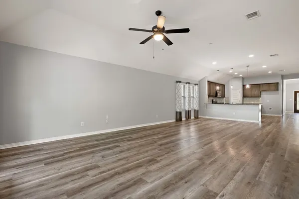 a view of empty room with wooden floor and ceiling fan
