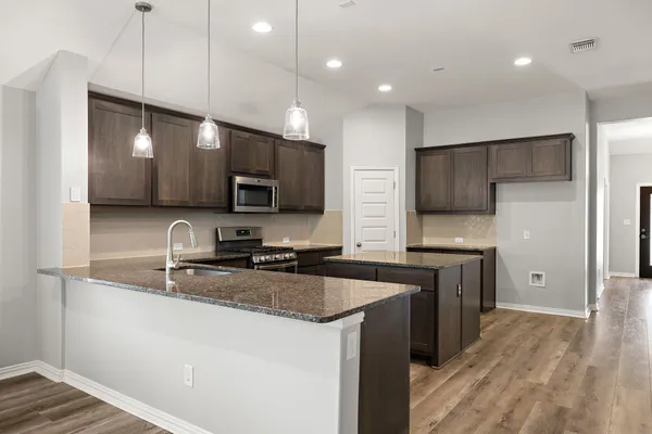 a kitchen with granite countertop a sink a counter top space stainless steel appliances and cabinets